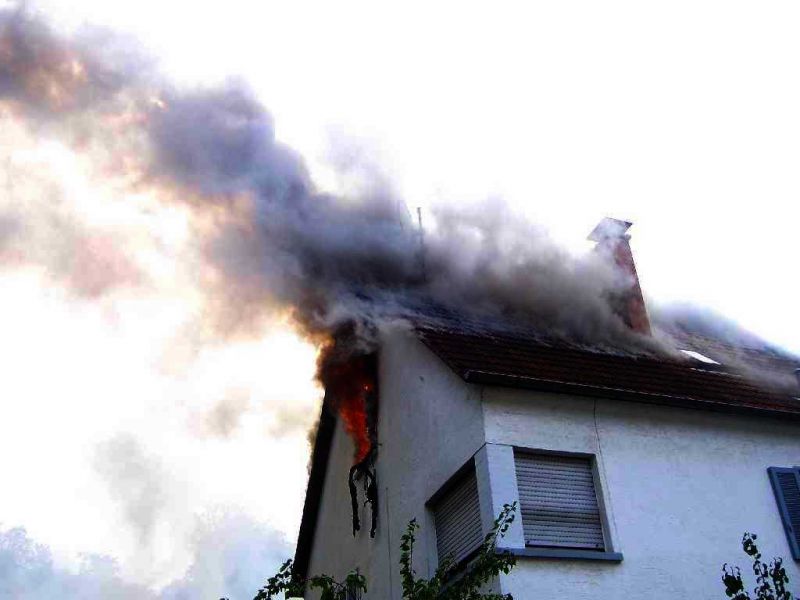Flammen schlagen aus dem Dachfenster
